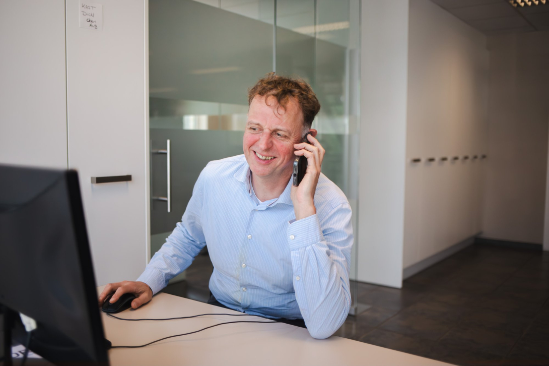 Man aan bureau telefoneert